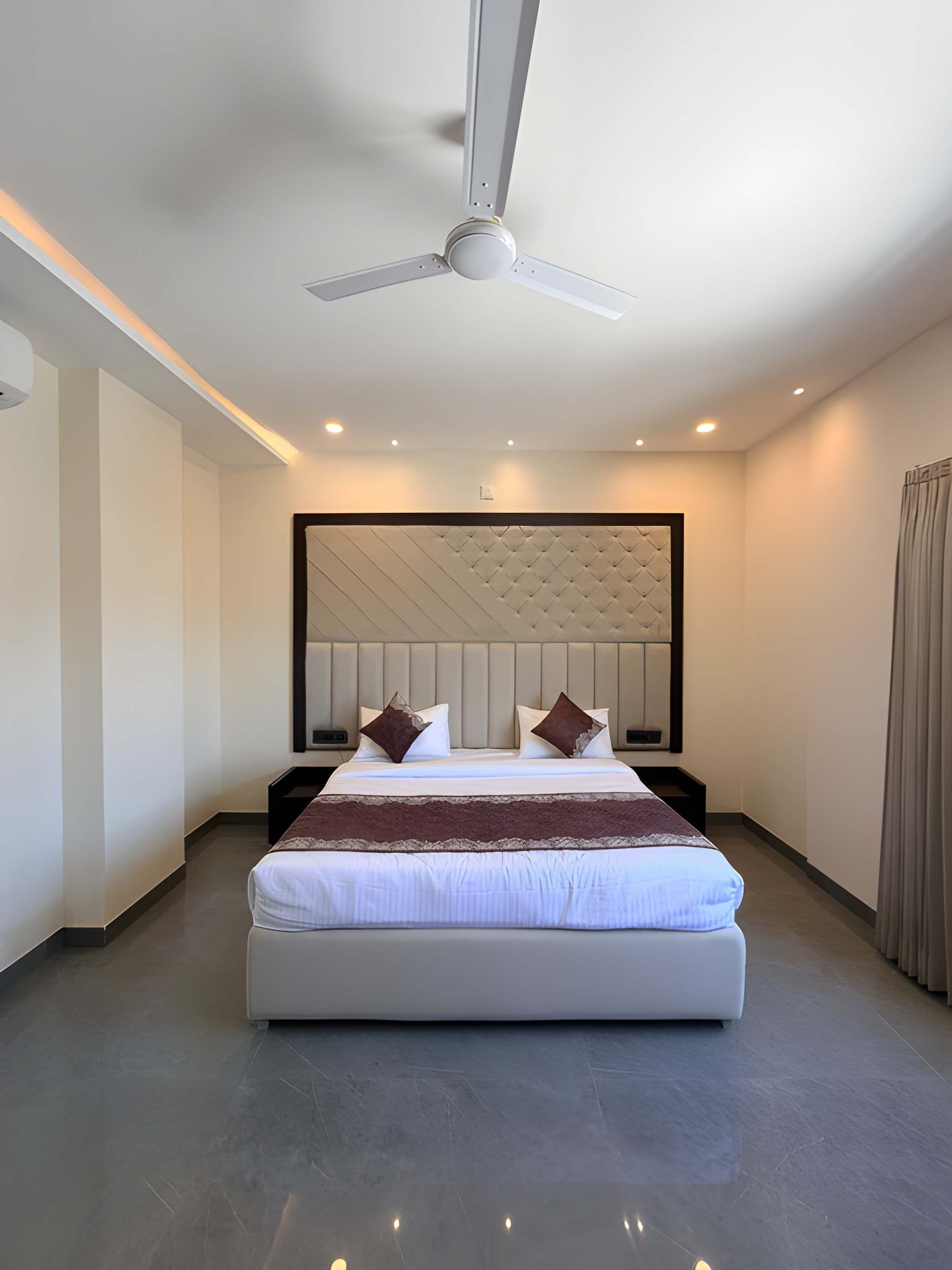 Una habitación de hotel moderna con una cama grande, ventilador de techo e iluminación empotrada.