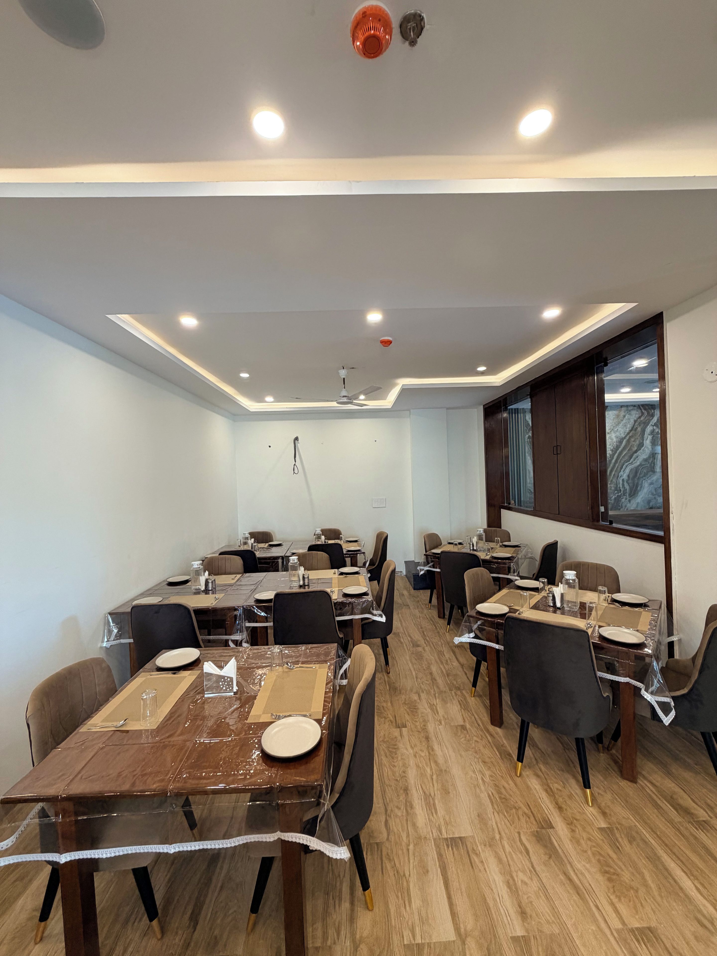 A conference room with multiple tables and chairs, equipped with ceiling lights and a ceiling fan.