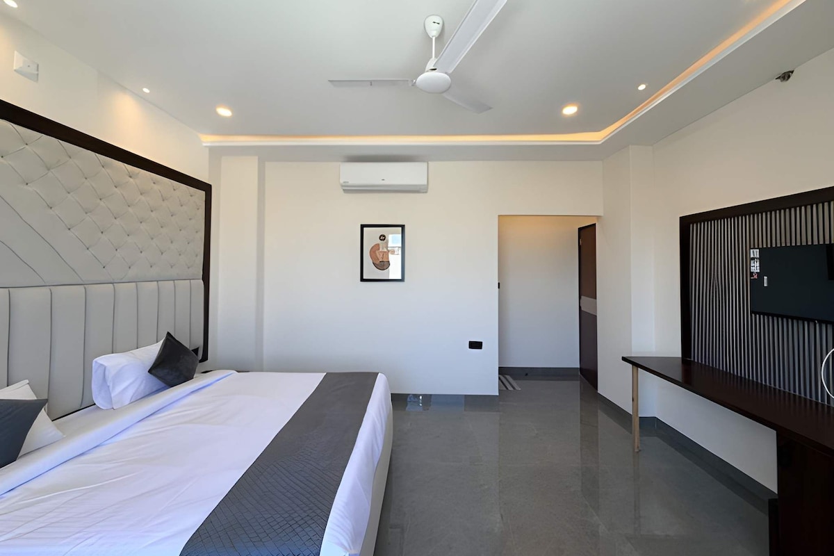 Una habitación de hotel moderna con una cama grande, ventilador de techo, iluminación empotrada, televisor de pantalla plana y una decoración minimalista.
