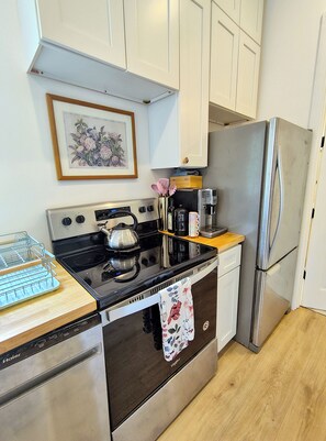 A kitchen with a stove, oven, refrigerator, and a coffee maker on the countertop. - Charming Cottage 1.5 miles from historic St. Augustine (St. Augustine)