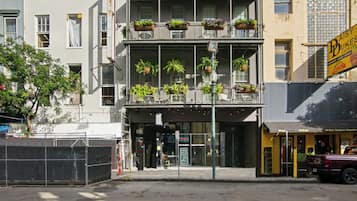 Een meerlaags gebouw met een begane grond ingang, een balkon met hangende plantenbakken en een zichtbaar bord voor Daisy Buksen Express.