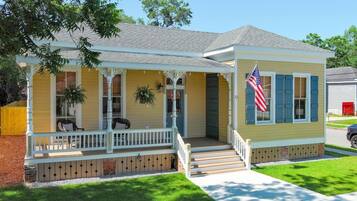 A single-story house with a porch, a flag, and a small front yard.
