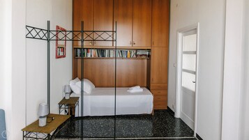 A compact bedroom with a bed, a bookshelf, and a door.