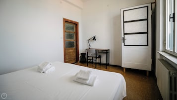 A hotel room with a bed, a desk, a chair, and a wardrobe.