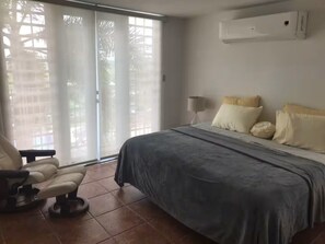 Een slaapkamer met een bed, een stoel, een lamp en een glazen schuifdeur.