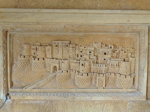 Un detallado relieve de piedra de una ciudad fortificada con múltiples torres y murallas.