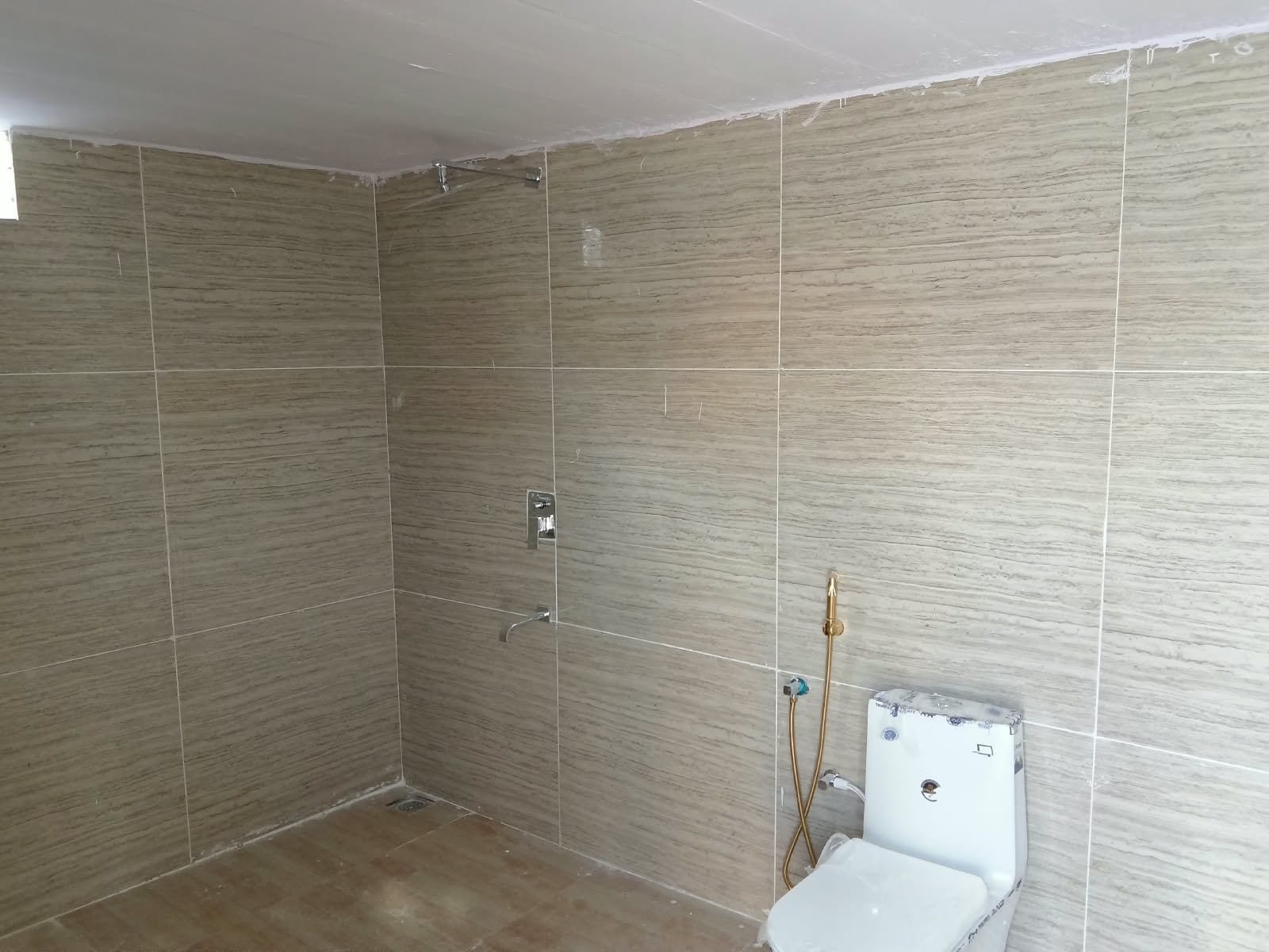 Un baño con paredes de azulejos, una ducha y un inodoro.