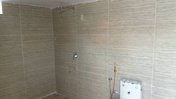 Un baño con paredes de azulejos, una ducha y un inodoro.