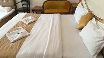 Una cama bien hecha con sábanas blancas, un cabecero de madera y una pequeña mesa de madera con una silla a un lado.