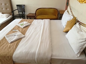 Una cama bien hecha con sábanas blancas, un cabecero de madera y una pequeña mesa de madera con una silla a un lado.