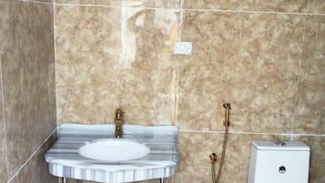 A bathroom with a marble sink, a toilet, and a shower.