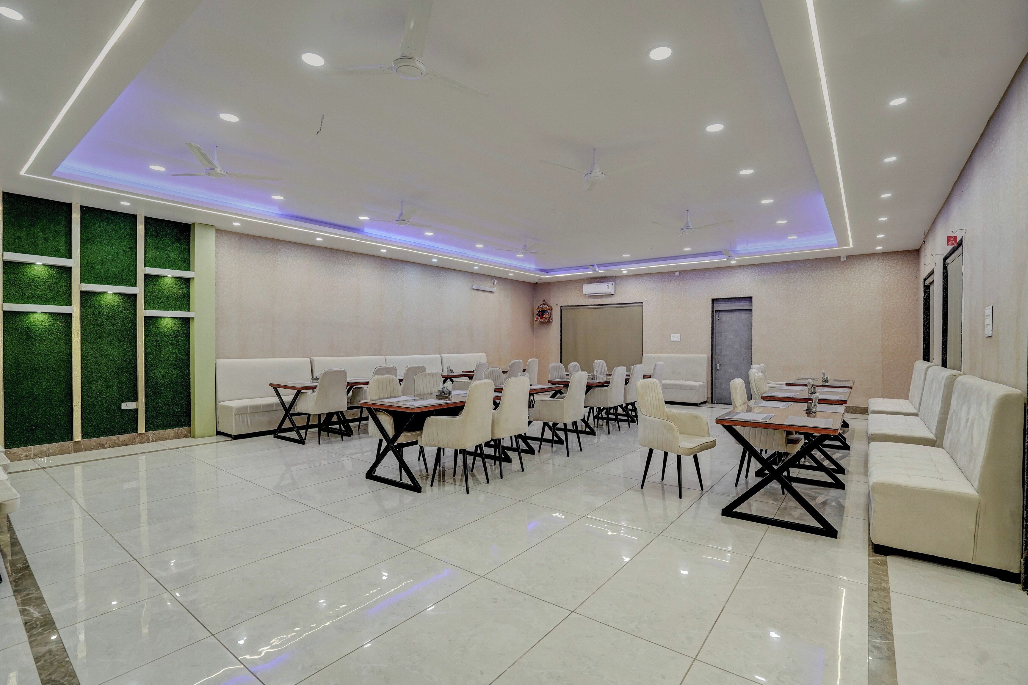 A conference room with white tables and chairs, a green wall, and a ceiling fan.