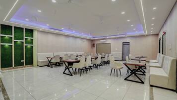 A conference room with white tables and chairs, a green wall, and a ceiling fan.
