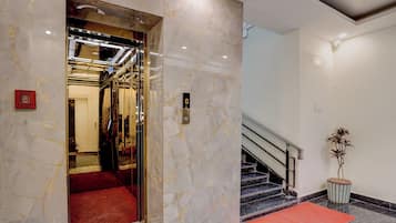 Un ascenseur doté d’un tapis rouge, d’un interrupteur d’arrêt d’urgence et d’un écran numérique.