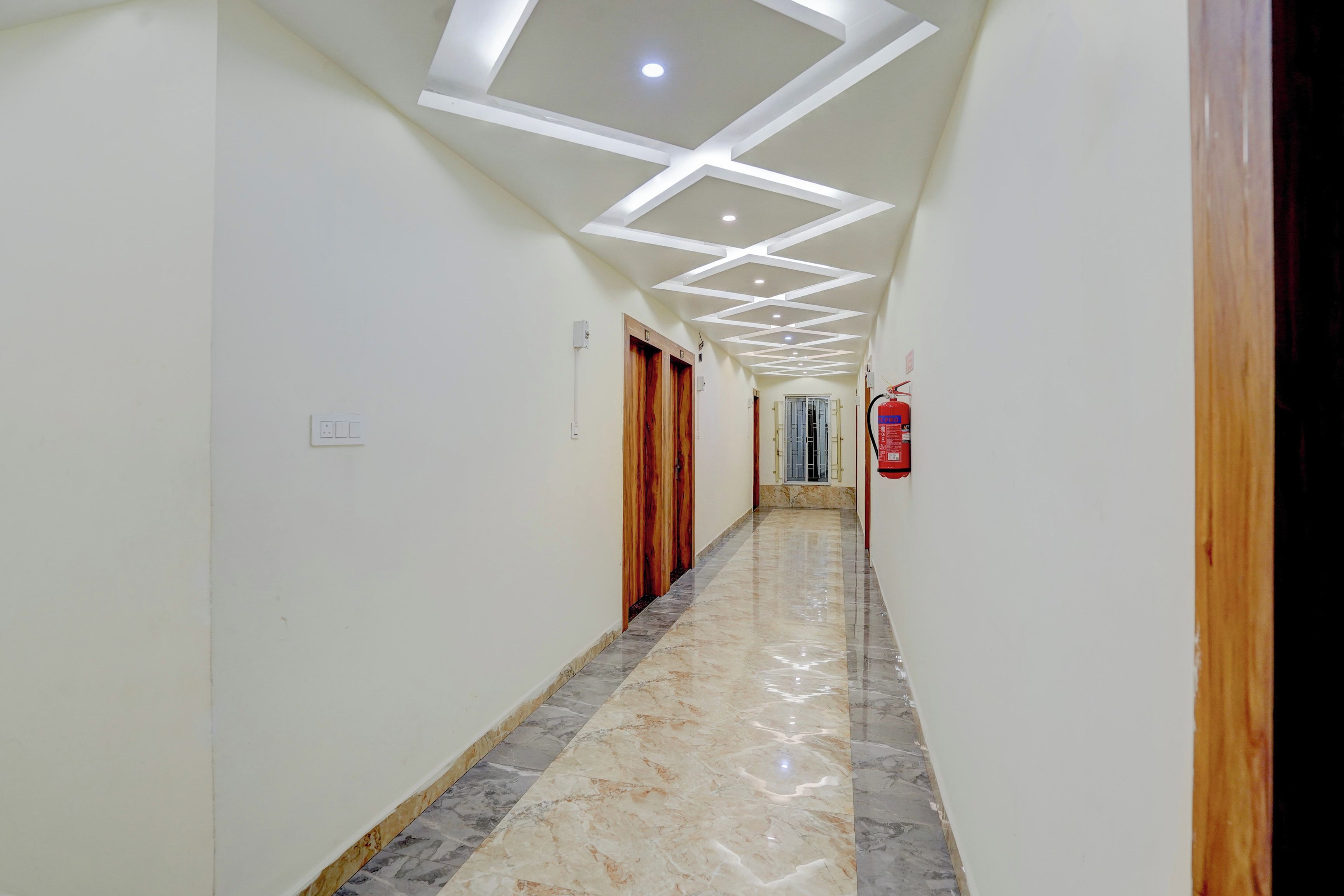 A hallway with a marble floor, white walls, and a ceiling with recessed lighting.