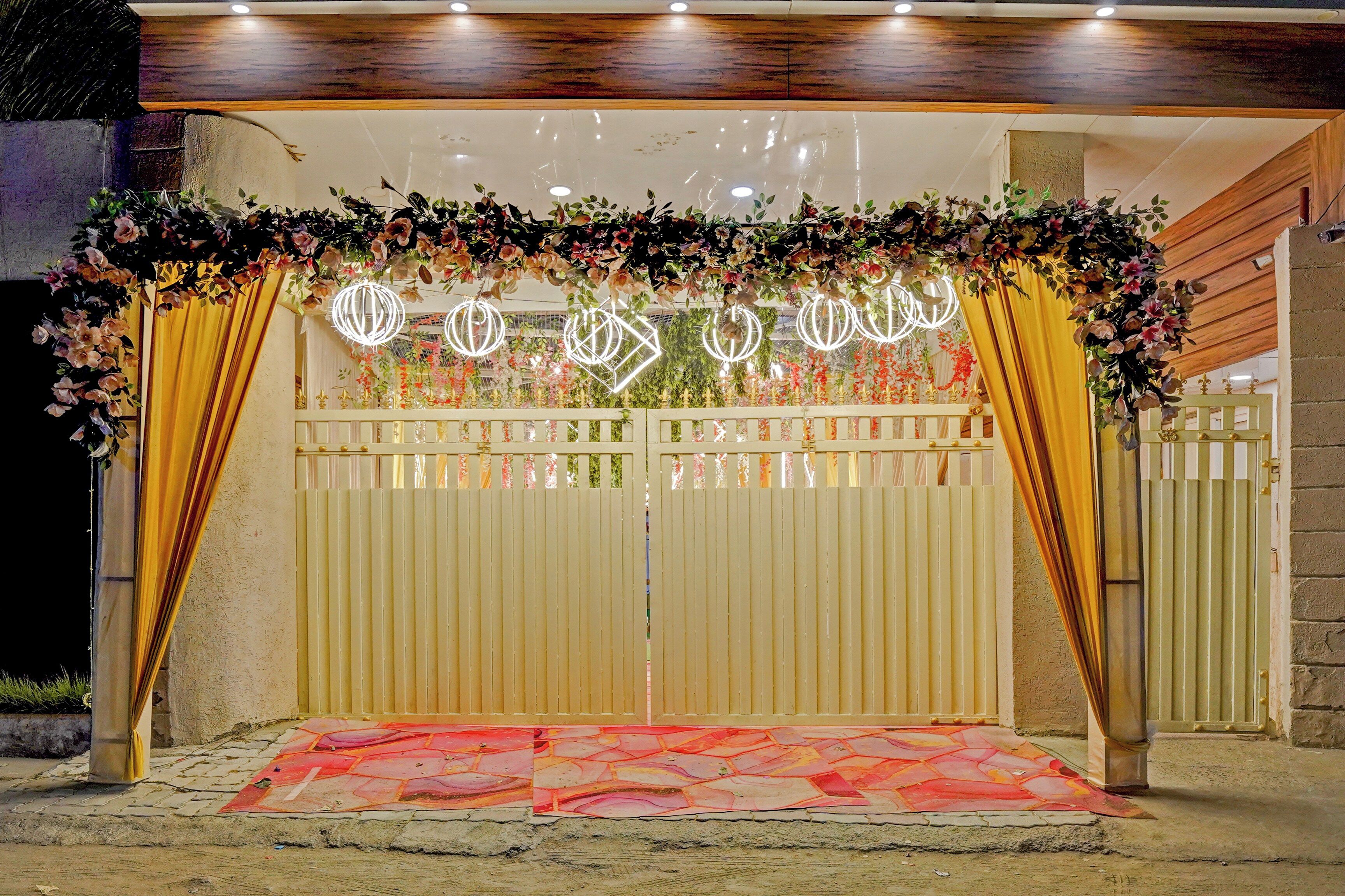 Una entrada protegida por una reja, con un arco floral y un suelo estampado.