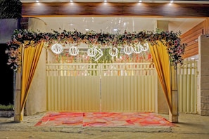 Una entrada protegida por una reja, con un arco floral y un suelo estampado.