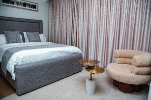 A bedroom with a bed, a round table, and a chair. - Villa De Fredwaa Unit 2 (Dar es Salaam)