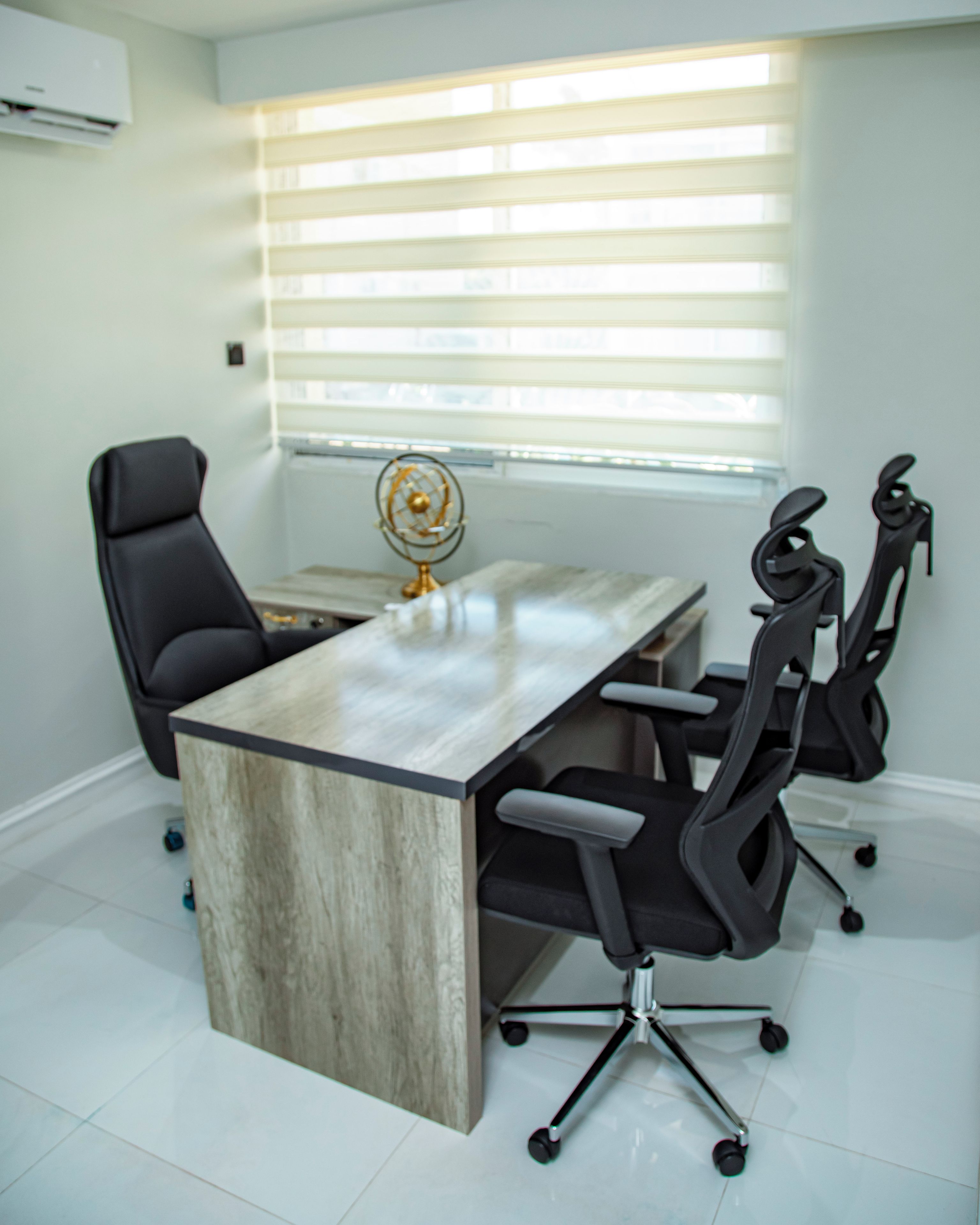 A modern office with a large table, black office chairs, and a globe decoration.