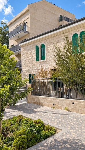 A building with a stone facade, green shutters, and a balcony. - Family Friendly Downtown Apartment with Free Parking By Isrentals (Jerusalem)