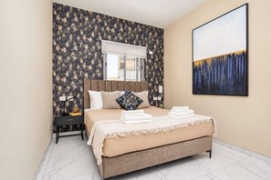 A hotel room with a bed, a nightstand, a window, and a painting on the wall. - Family Friendly Downtown Apartment with Free Parking By Isrentals (Jerusalem)