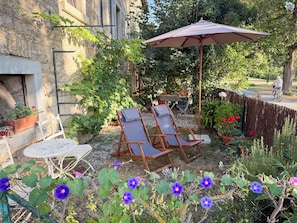 A patio with two lounge chairs, a table, and a large umbrella. - A cosy autumn and winter retreat in the historic ferryman’s house on the Main (Winterhausen)