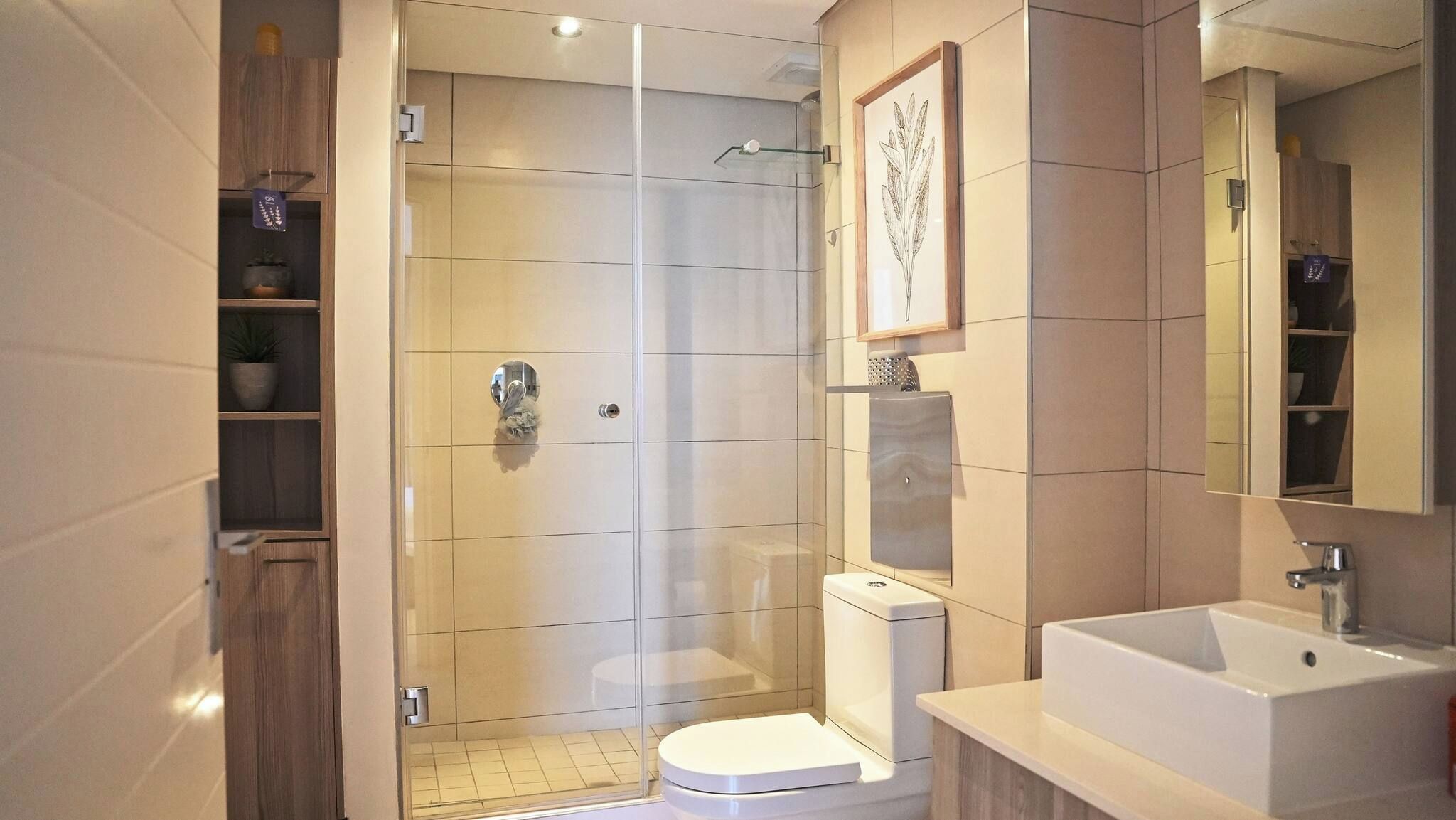 Ein modernes Badezimmer mit einer gläsernen Dusche, einer Toilette und einem Waschbecken.