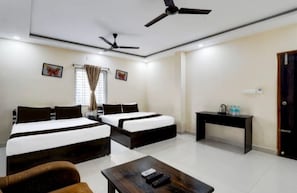 Habitación de hotel con dos camas, un escritorio, una silla, ventilador de techo y ventana con cortinas.