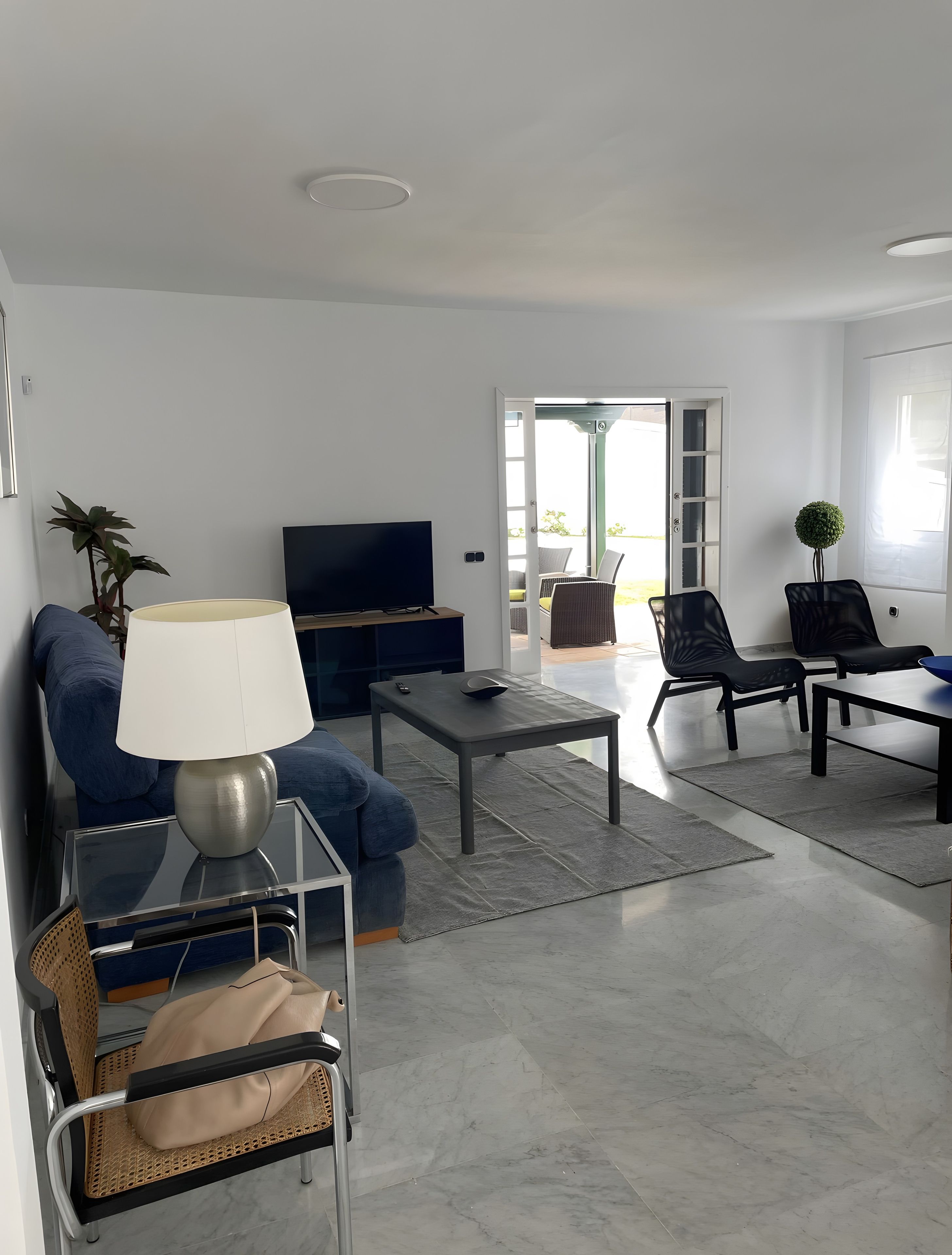 A modern living room with a sofa, coffee table, TV, and dining area.