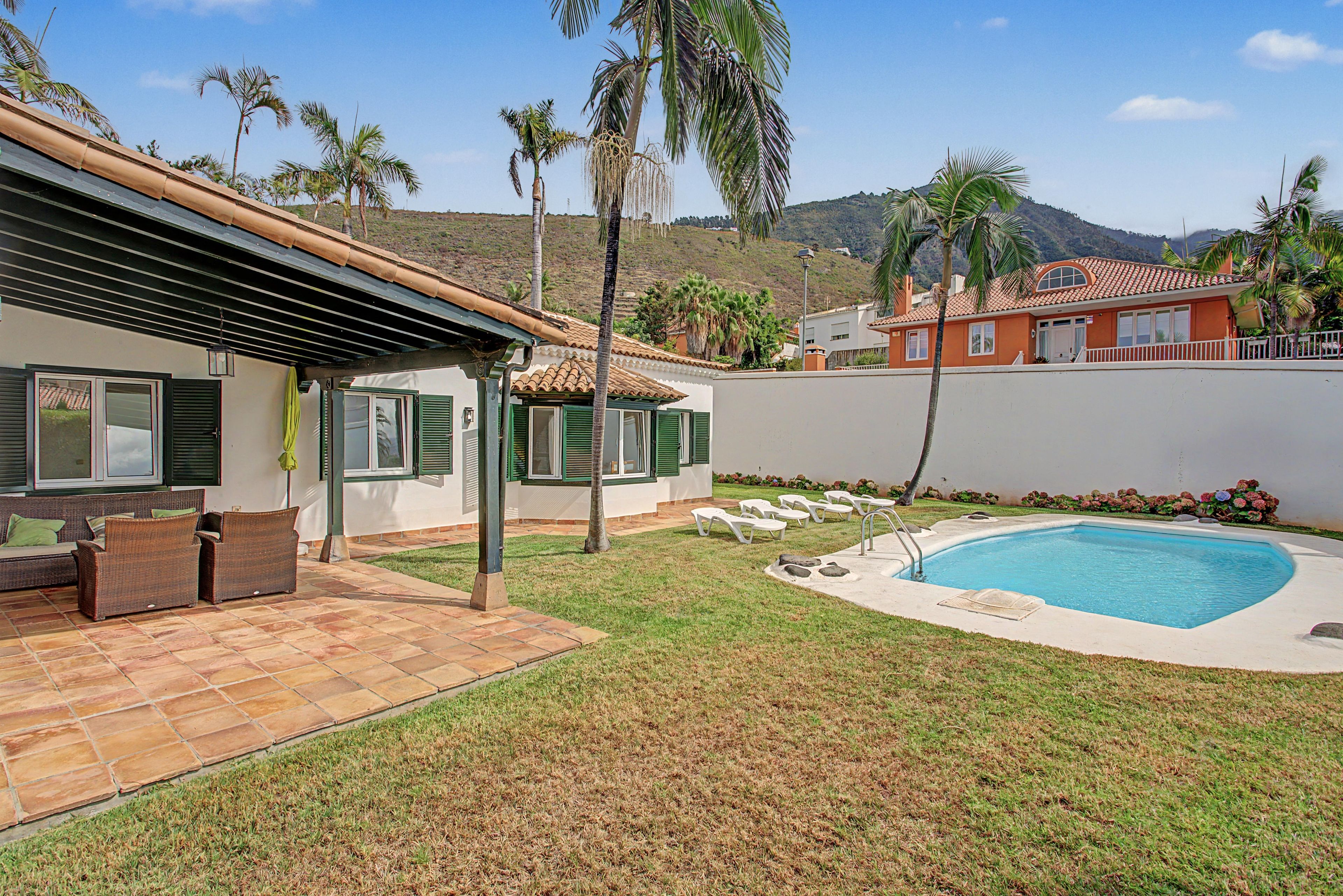 Una propiedad residencial con piscina, mobiliario de patio y vista a un paisaje montañoso.