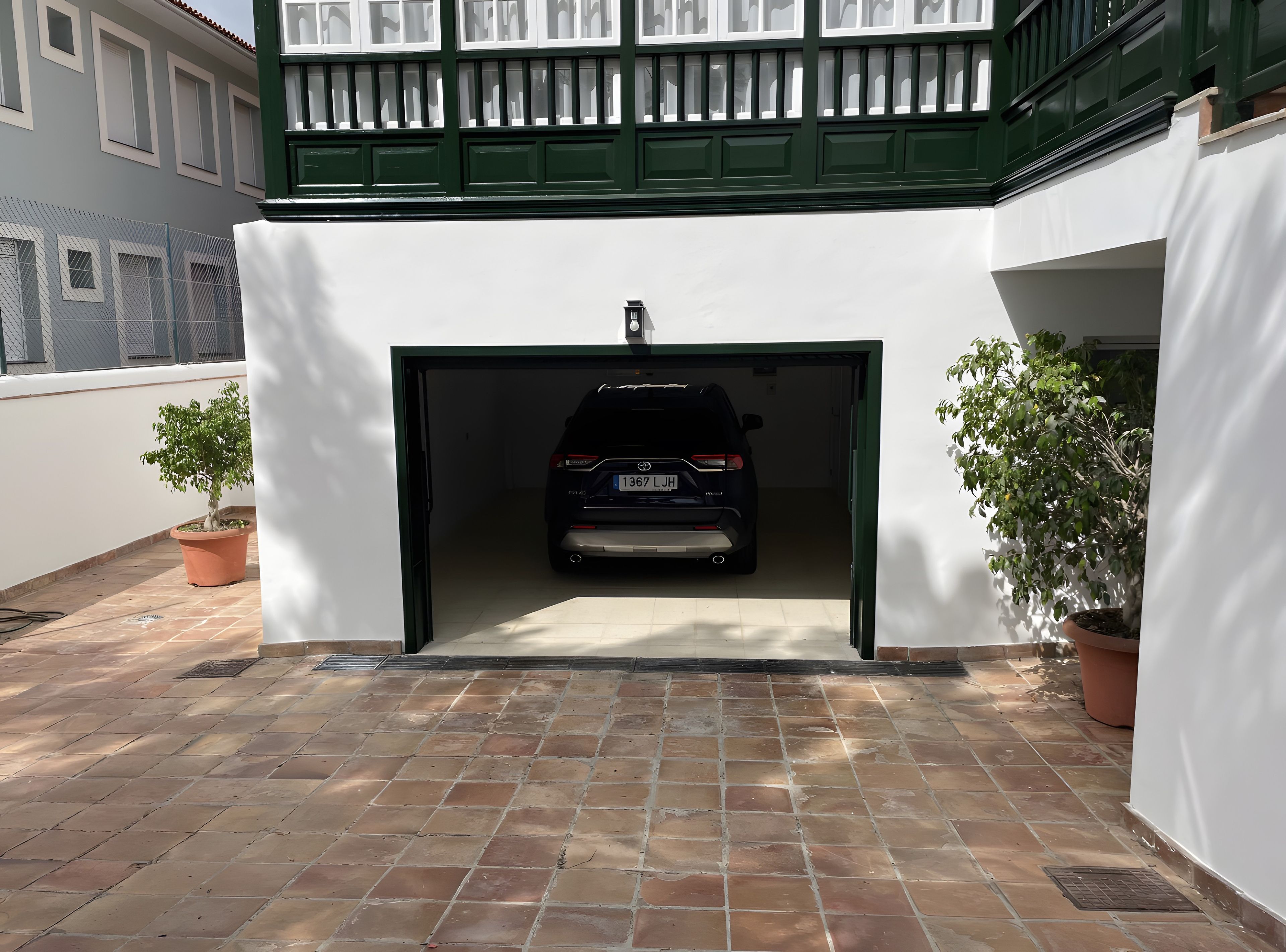 A car parked inside a garage with a white wall and green trim.
