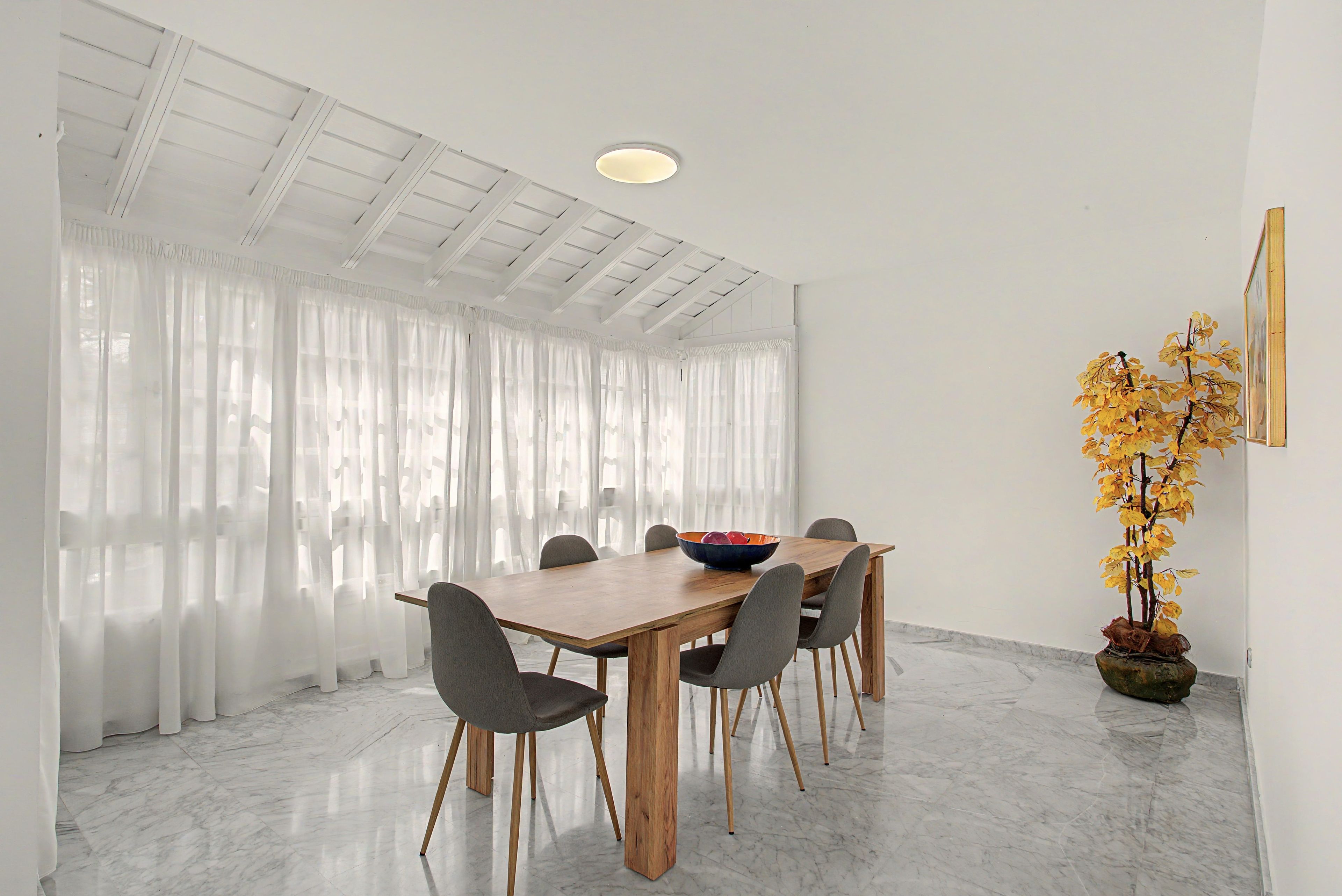A dining area with a wooden table, grey chairs, and a bowl on the table.