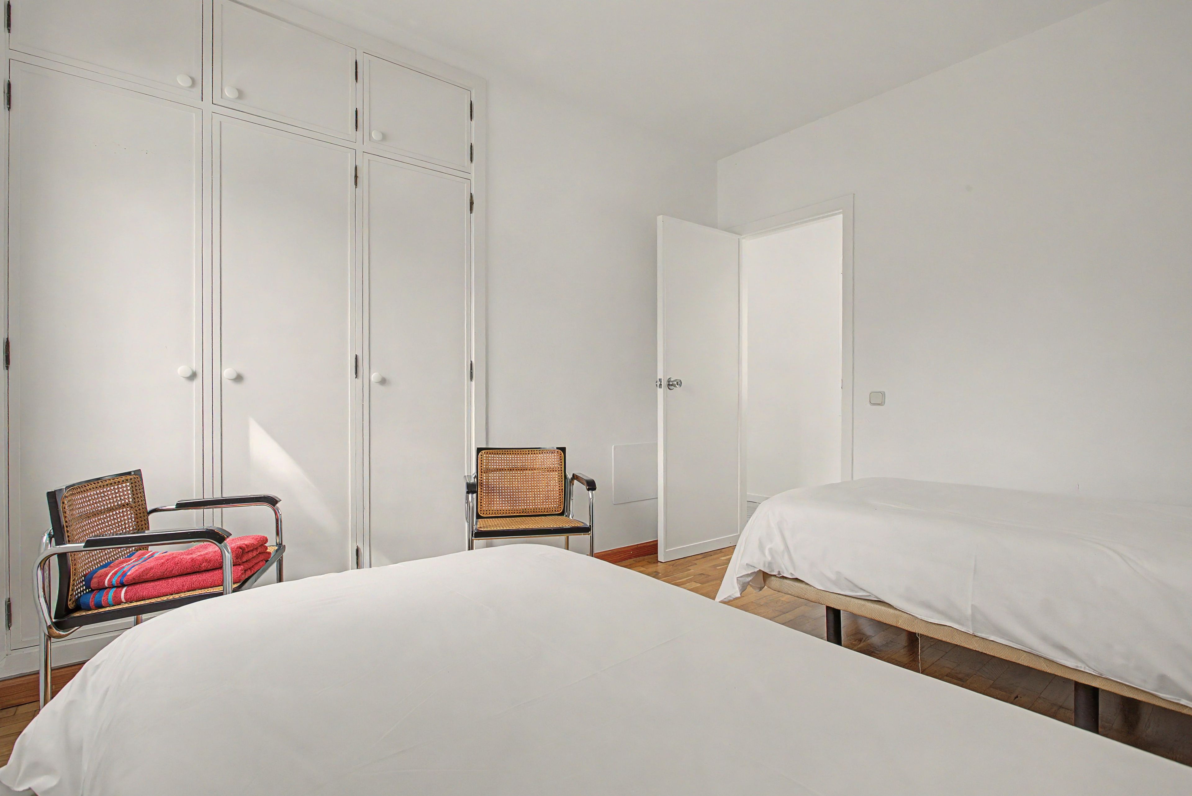 Ein Schlafzimmer mit zwei Betten, einem Sessel und einem Kleiderschrank.