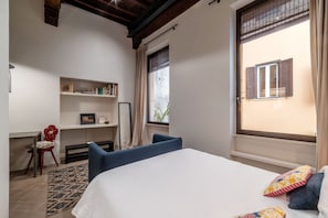 A bedroom with a bed, a desk, a chair, a shelf with books, and a window with shutters. - Coronari 3 - FromHometoRome (Roma)