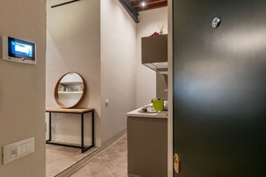 Ein modernes Badezimmer mit Spiegel, Waschbecken und Toilette. Über dem Waschbecken befindet sich ein kleines Regal mit Pflegeprodukten und ein Handtuchhalter.