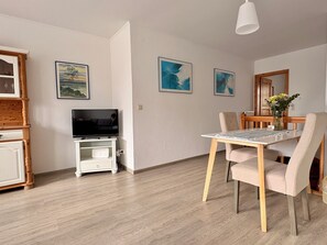 A modern living room with a flat-screen TV, wooden furniture, and artwork on the walls. - Fischerstuuv - 50-square-meter apartment for 2 in downtown Husum (Husum)