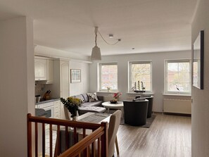 A modern interior with a dining area, kitchen, and seating space. - Fischerstuuv - 50-square-meter apartment for 2 in downtown Husum (Husum)