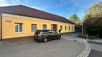 Ein Gebäude mit gelber Fassade, ein geparktes Auto und ein klarer Himmel.