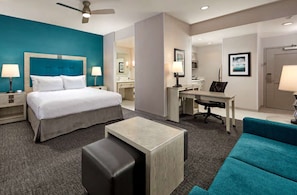 Ein Hotelzimmer mit Bett, Schreibtisch, Stuhl und einem kleinen Hocker.