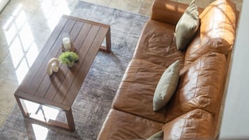 A brown leather sofa with cushions and a wooden coffee table with a small plant and candle.