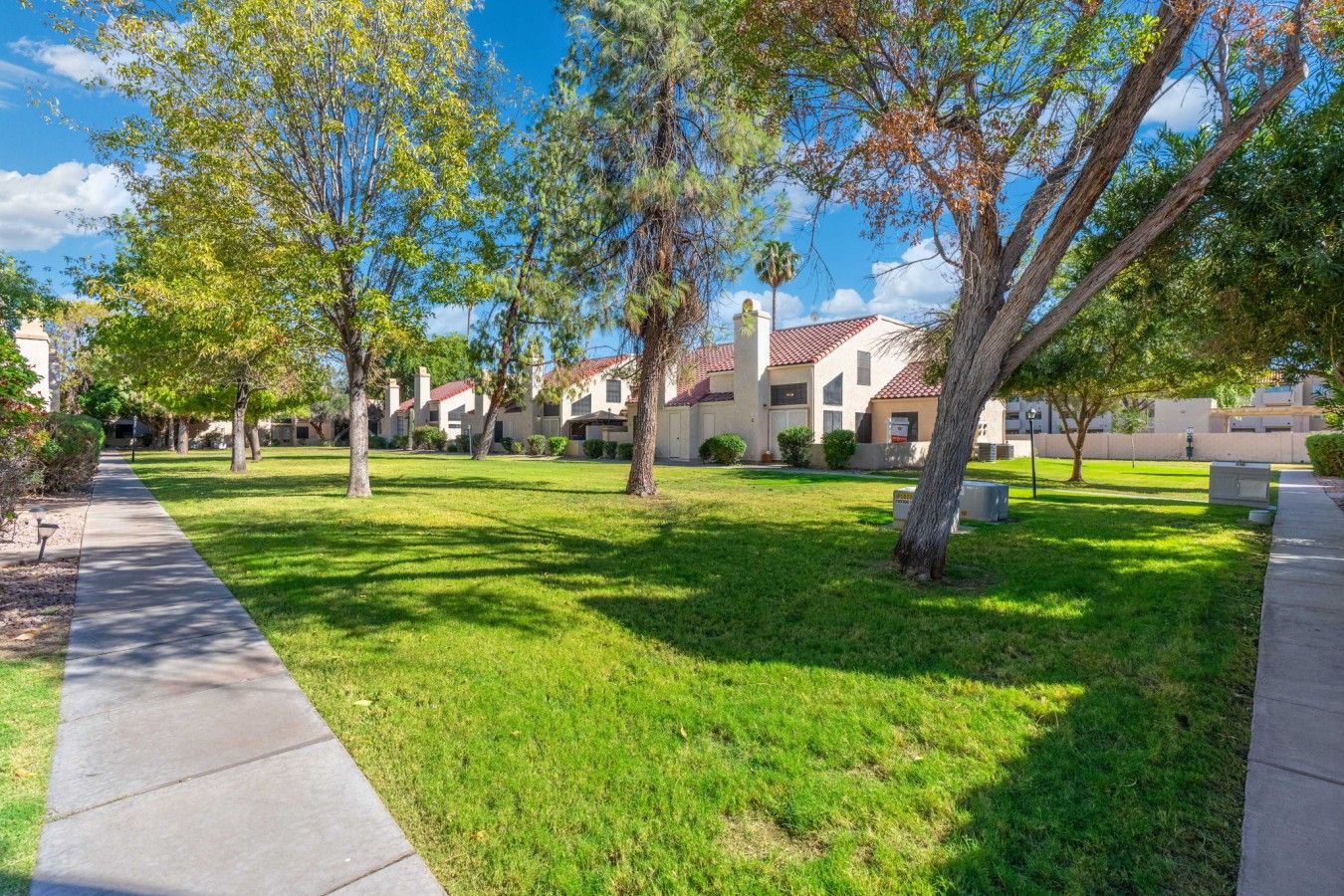 Un barrio residencial con un camino empedrado, céspedes verdes y casas con techos de tejas rojas.
