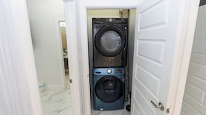 A laundry room with two stacked washing machines, a white door, and a tiled floor. - Private Pool Entire 6BR Duplex (South Padre Island)