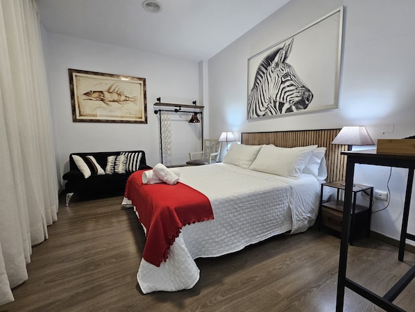 A hotel room with a bed, a nightstand, a lamp, a zebra painting, and a fish illustration on the wall.