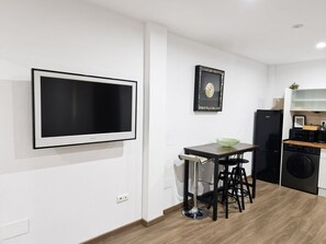 Eine moderne Küche mit Flachbildfernseher, einer gerahmten Uhr, einem Spülbecken und einer Waschmaschine.