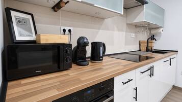 Una cocina moderna con microondas, cafetera y un reloj digital.
