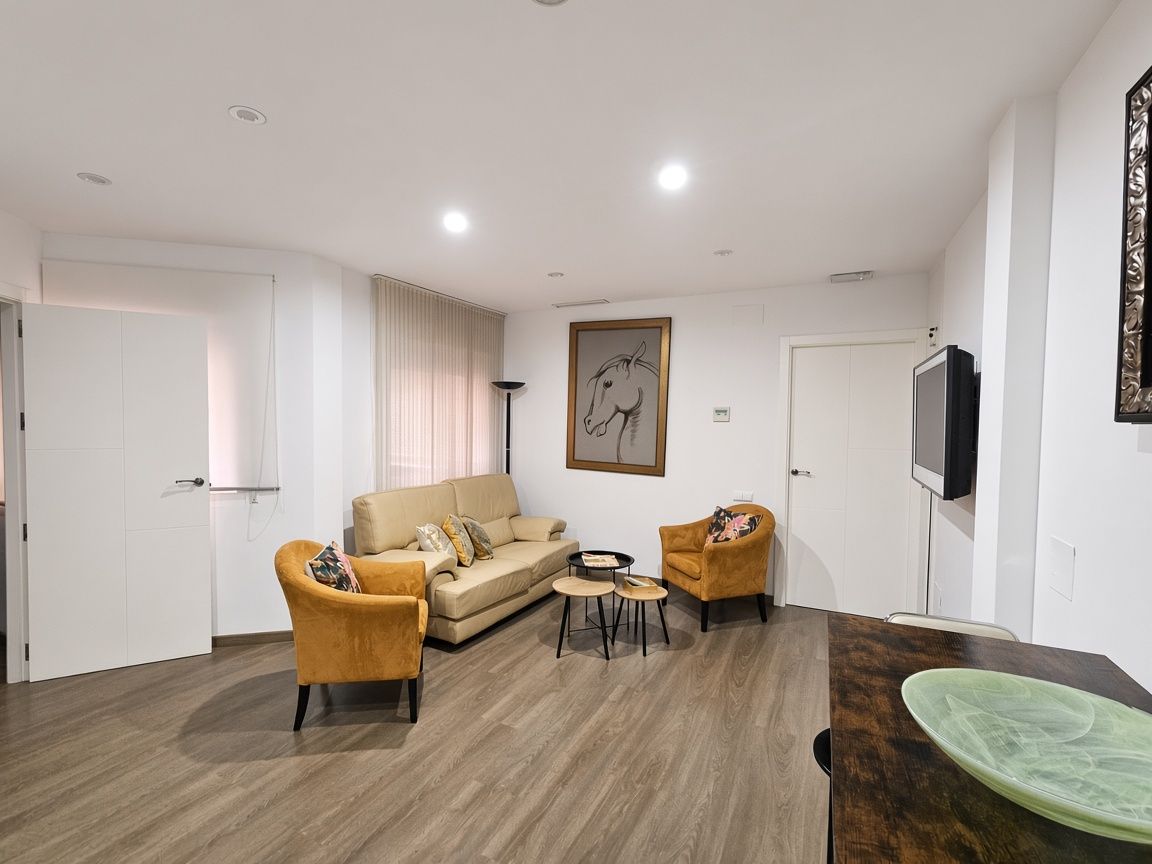 Una sala moderna con un sofá, dos sillones, una mesa de centro y un televisor.