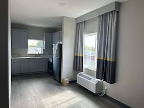 Eine kompakte Küche mit integriertem Mikrowellenherd, einem Kühlschrank und einem Fenster mit Vorhängen.