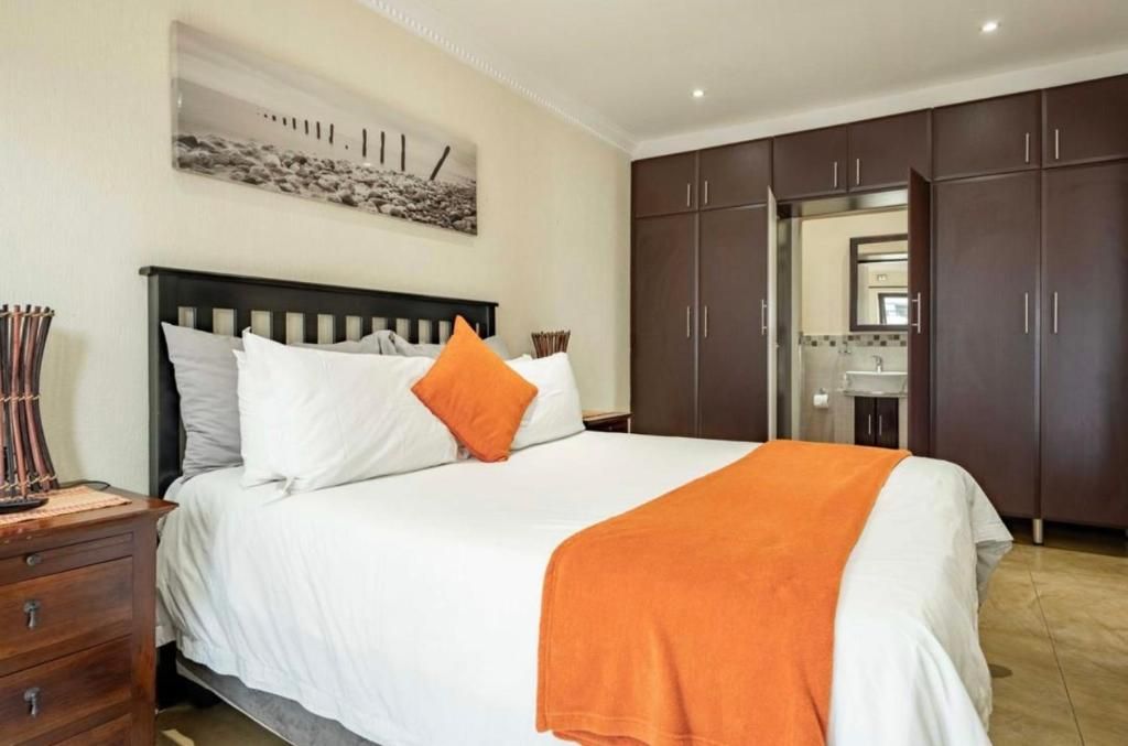 Une chambre à coucher avec un lit, une table de chevet, une commode et un miroir.