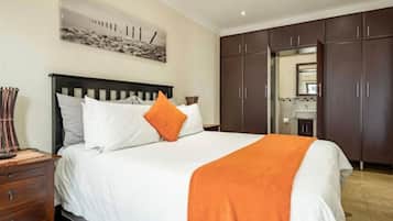 Une chambre à coucher avec un lit, une table de chevet, une commode et un miroir.