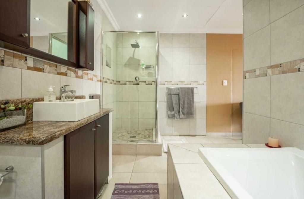 Une salle de bain moderne équipée d’une douche, d’une baignoire et d’un meuble-lavabo avec un évier.